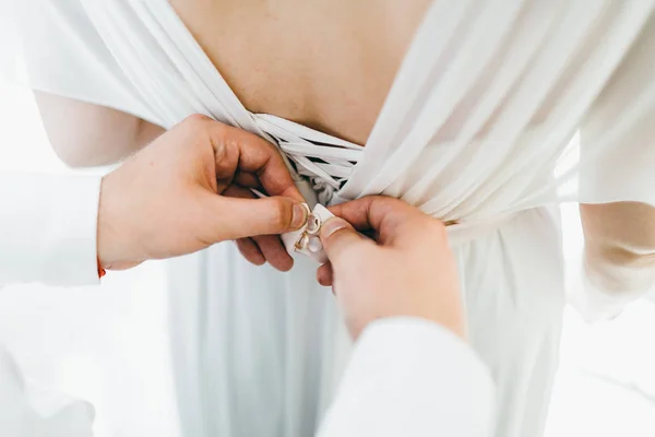 Brudgummen hjälper fäst en bröllopsklänning bruden före vigseln. Bröllop koncept. Närbild konstverk — Stockfoto