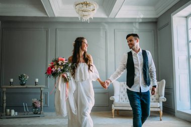 Neşeli gelin ve damat elele. Gülüyor ve birbirine bakarak yeni evliler. Sanat. Kapalı düğün. Yumuşak odak