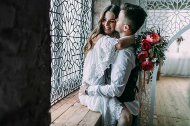 Süre o yanak içinde onu öper ve beline pencere üzerinde kucaklayan neşeli genç gelin sarılma damat