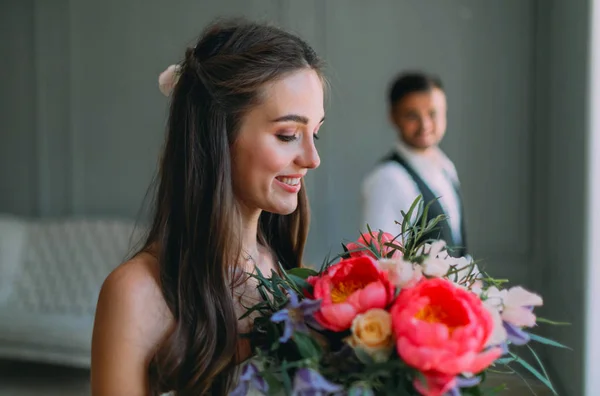 Gros plan portrait d'une jeune mariée joyeuse avec un bouquet de mariage sur fond de marié flou. Une fille heureuse avec un bouquet de fleurs — Photo