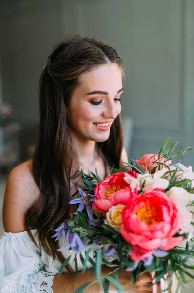 Neşeli, genç gelin bir rustik düğün buketi beyaz güller ve Kızıl peonies ile tutar. Yakın çekim portre. Çiçek bir demet mutlu bir kızla