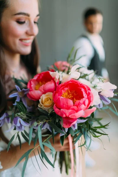 Detailní portrét veselá, mladá nevěsta s svatební kytice na pozadí rozmazané ženicha. Šťastná dívka s kytice — Stock fotografie