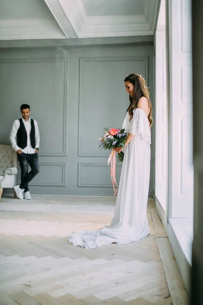 Vrolijke, jonge bruid houdt een rustieke bruiloft boeket met pioenrozen op panoramische raamachtergrond. Close-up portret. Een gelukkig brunette meisje met een bos van bloemen. — Stockfoto