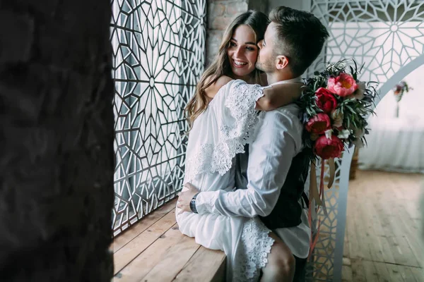 Süre o yanak içinde onu öper ve beline pencere üzerinde kucaklayan neşeli genç gelin sarılma damat