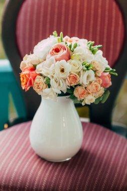 Klasik ahşap sandalye üzerinde cam vazoda beyaz ve şeftali gül düğün buketi. Sanat
