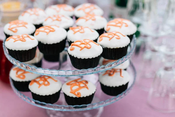 Cupcakes med initialerna för bruden och brudgummen på en två-nivå monter på ett bröllop — Stockfoto