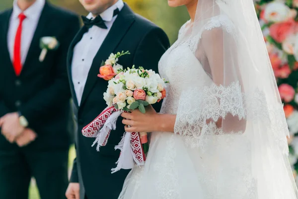 De mooie bruid houdt een bruiloft boeket met roze rozen en pioenrozen. De ceremonie van het huwelijk in proces — Stockfoto