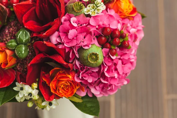 Bouquet de mariage rustique avec des roses orange, cramoisi et bordeaux, coquelicot et autres fleurs et verts sur fond en bois. Gros plan . — Photo