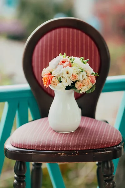 Wedding bouquet of white and peach roses in a glass vase on the classic wooden chair. Artwork — Stock Photo, Image