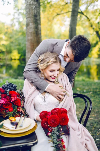 El guapo novio abrazando a su novia en la mesa festiva. Boda de otoño. Obra de arte — Foto de Stock