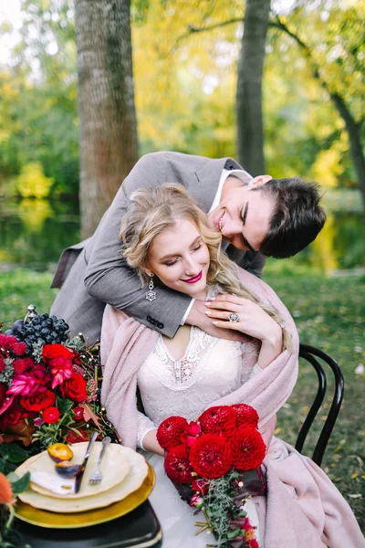 El guapo novio abrazando a su novia en la mesa festiva. Boda de otoño. Obra de arte — Foto de Stock