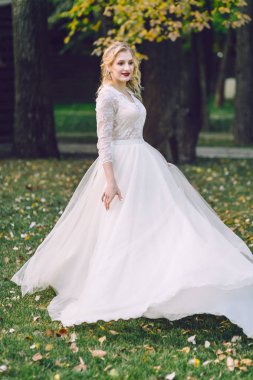 Güzel gelin kendini dans dönüyor. Gülümseyen kadın açık havada çırpınan elbiseyle poz. Düğün. Sanat