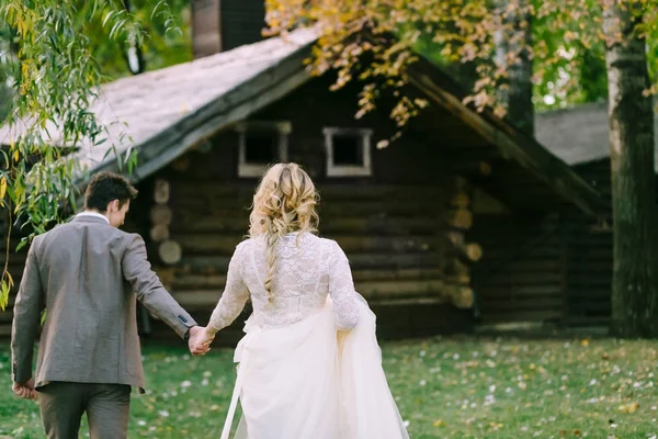 Наречений і наречений йдуть до дерев'яного будинку в лісі. Осіннє весілля. Художня робота — стокове фото