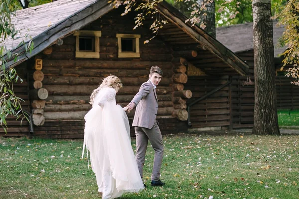 新郎把他的新娘带到森林里的木房子里。秋季婚礼艺术品 — 图库照片