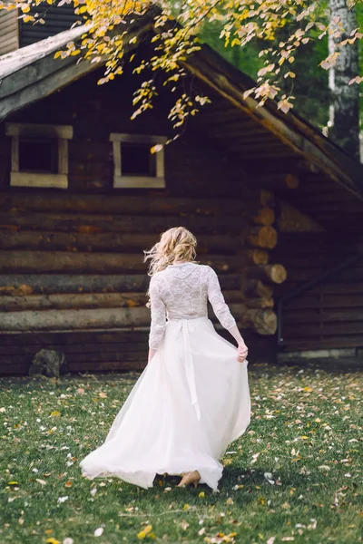 Блондинка невеста ходит в трепещущем платье на деревянном фоне дома. Вид сзади. Озил работает — стоковое фото