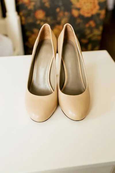 Chaussures beiges sur les talons d'une mariée sur une surface de table blanche. Préparation du mariage. Oeuvres — Photo