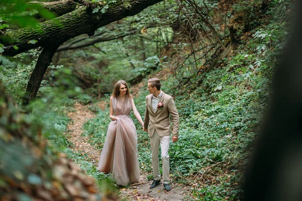 Ett lyckligt par går på en stig i en höst skog. Brudparet tittar på varandra på naturen. — Stockfoto