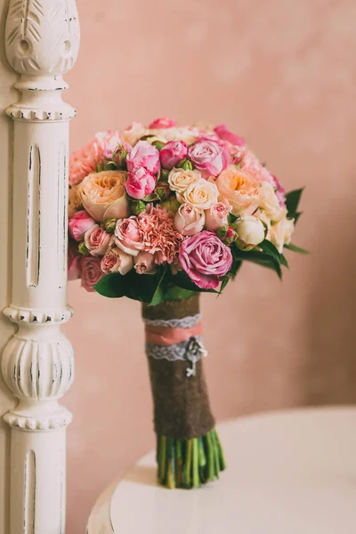 Bridal bouquet with pink roses and peach peonies stands on background of vintage wall