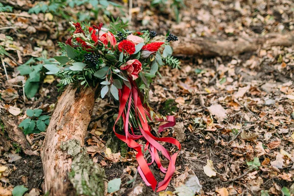 Beautiful wedding bouquet of different flowers lying on a log in the park. Autumn wedding — Stock Photo, Image