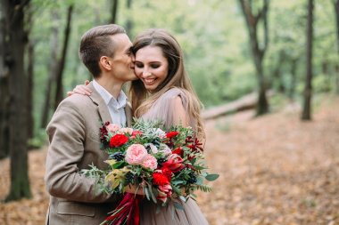 Damat şefkatle ona güzel gelin yanak içinde öpüşme. Sonbahar düğün töreni rustik tarzda. Yeni evliler