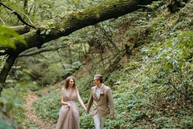 Şık yeni evliler niteliğine güzel bir romantik yerde bir iz üzerinde dolaşıyor. Düğün töreni açık havada.