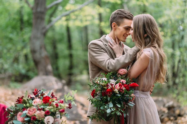 Cerimônia de casamento de outono ao ar livre. noiva elegante e noivo abraçando uns aos outros na floresta — Fotografia de Stock