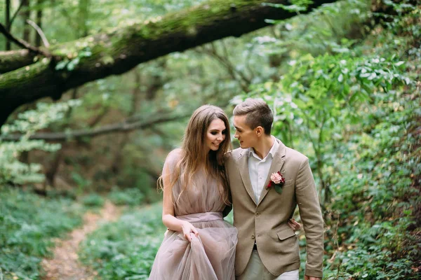 A stylish bride and groom is walking on a trail in an autumn forest. Wedding ceremony outdoors. — Stock Photo, Image