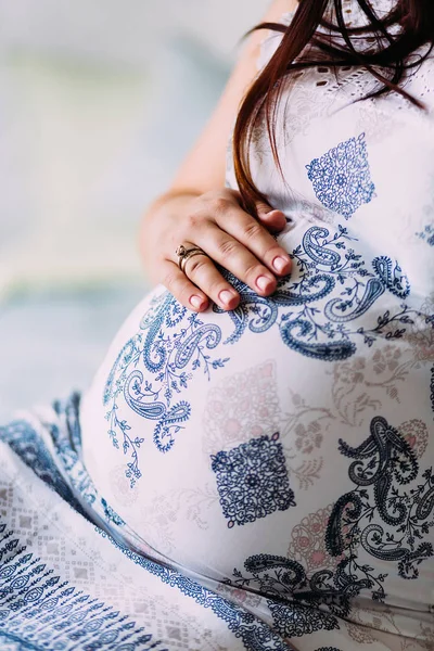 Una mujer embarazada toca su vientre. Mano con un anillo en la barriga. Obras de arte. Primer plano . —  Fotos de Stock