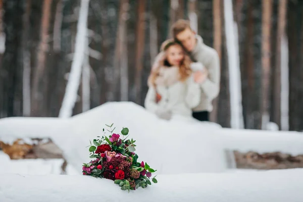 Braut und Bräutigam sitzen auf dem Baumstamm im Winterwald. Nahaufnahme. Winterhochzeit. weiche Konzentration auf das Bouquet — Stockfoto