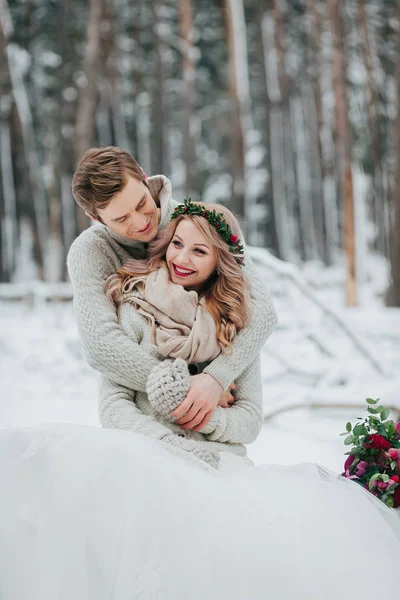 Glückliche Frischvermählte liegen sich im Winterwald in den Armen. verliebtes Paar. Winterhochzeit. — Stockfoto