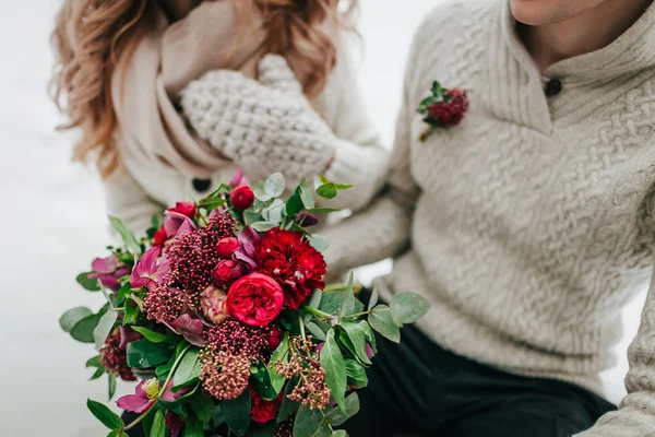 Bouquet da sposa con fiori rossi e cremisi su sfondo sfumato sposa e sposo. Matrimonio invernale all'aperto — Foto Stock