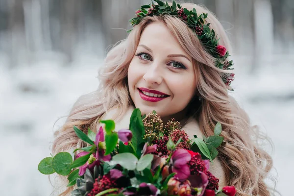Volto di una ragazza sorridente di aspetto slavo con una corona. Bella sposa tiene un bouquet sullo sfondo invernale . — Foto Stock