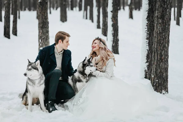 Groom embrasse sa fiancée sur le temple sur fond de neige blanche. Mariage d'hiver. Une oeuvre. Focus sélectif sur le bouquet — Photo