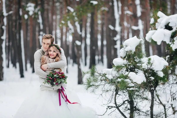 Stylisches Brautpaar umarmt sich im Winterwald. Winterhochzeit. Kunstwerk. — Stockfoto