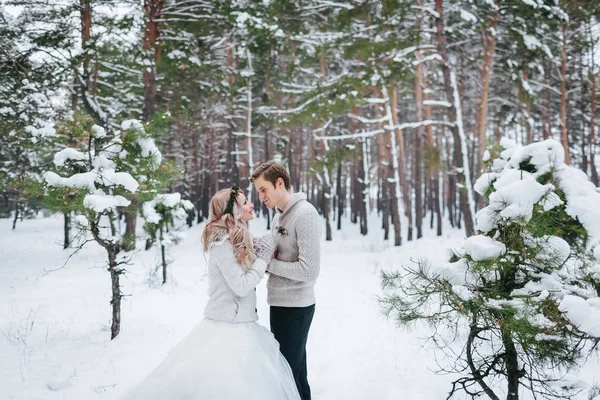 Joyeux marié et mariée en pull tricoté beige dans la forêt enneigée. Les jeunes mariés se regardent. Hiver — Photo