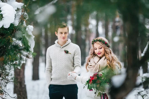 Mariée gaie et marié en pull tricoté beige marchent dans la forêt enneigée. Concentration sélective sur la mariée. Oeuvres — Photo