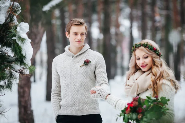 Mariée gaie et marié en pull tricoté beige marchent dans la forêt enneigée. Concentrez-vous sur le marié. Oeuvres — Photo