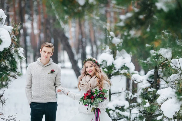 Novia alegre y novio en pullovers de punto beige están caminando en el bosque nevado. Enfoque selectivo en la novia. Obra de arte —  Fotos de Stock