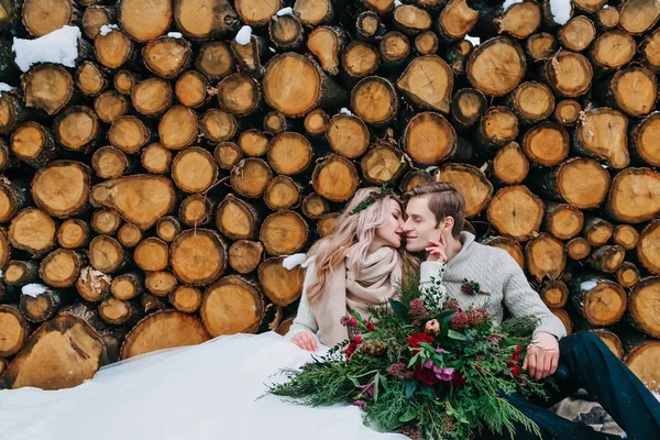 Winter wedding bouquet. Artwork. Couple sits on snow on the wooden background. — Stock Photo, Image