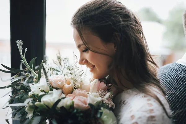 Joyeuse, jeune mariée tient un bouquet de mariage rustique. Portrait en gros plan. Une fille heureuse avec un bouquet de fleurs — Photo