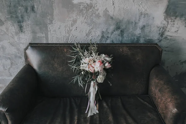 Rustic floral composition with light roses and other flowers on a luxury brown sofa.. — Stock Photo, Image