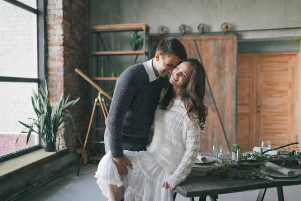 Recién casados riendo y besándose en la mesa de la cocina — Foto de Stock