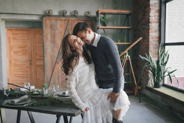 Jeunes mariés riant et s'embrassant sur la table de cuisine — Photo
