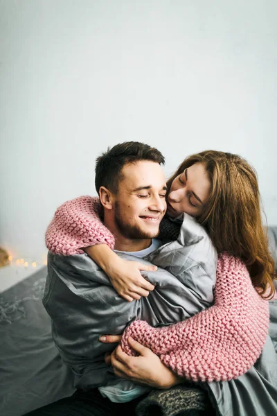 Bonito jovem mulher abraçando e beijar seu namorado. Um casal a divertir-se na cama. Obra. Foco suave — Fotografia de Stock