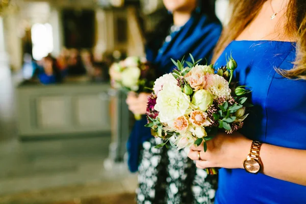 Photo en gros plan de demoiselles d'honneur tenant des bouquets de fleurs dans l'église pendant la cérémonie de mariage. Oeuvres — Photo