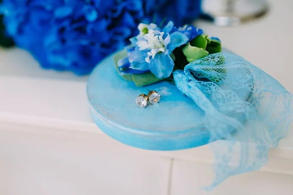 Brincos de prata com pedras preciosas em um suporte de madeira, com uma hortênsias azul no fundo. Casamento. Obra de arte — Fotografia de Stock