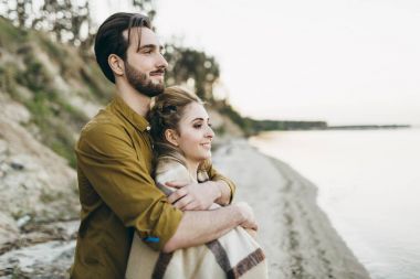 Güzel bir çift sarılıyor ve gün batımı hayran. Sahilde romantik tarih. Düğün. Sanat.