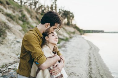 Güzel bir çift sarılıyor ve gün batımı hayran. Sahilde romantik tarih. Düğün. Sanat.