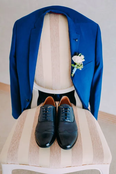 Auf einem Stuhl liegen schwarz lackierte Schuhe eines Bräutigams. vor dem Hintergrund des Smokings des Bräutigams — Stockfoto