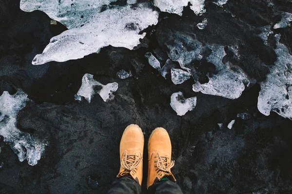 旅行者在徒步旅行靴站立在黑沙子。冰岛。顶部视图 — 图库照片